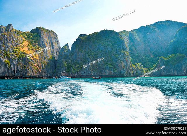 Panorama of famous Phi Phi island in Thailand with white waves stream behind speed boat, sea and mountains in beautiful lagoon
