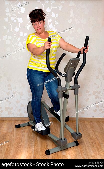 young plump woman exercising on trainer ellipsoid