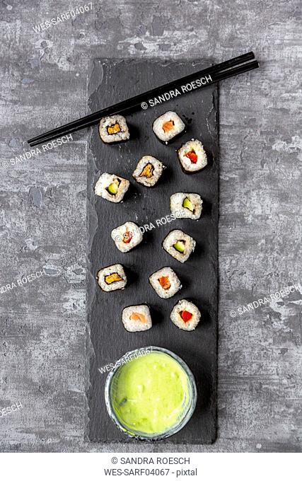 Sushi on slabe plate, wasabi in bowl, chop sticks