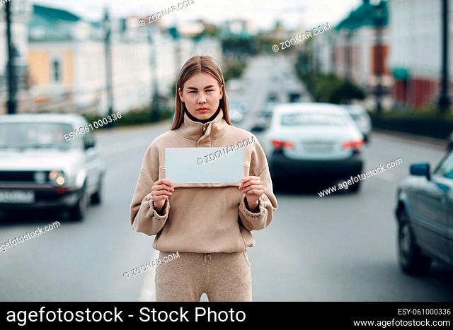 Young woman hold white paper poster in hand. Girl with white blank template sheet in hands