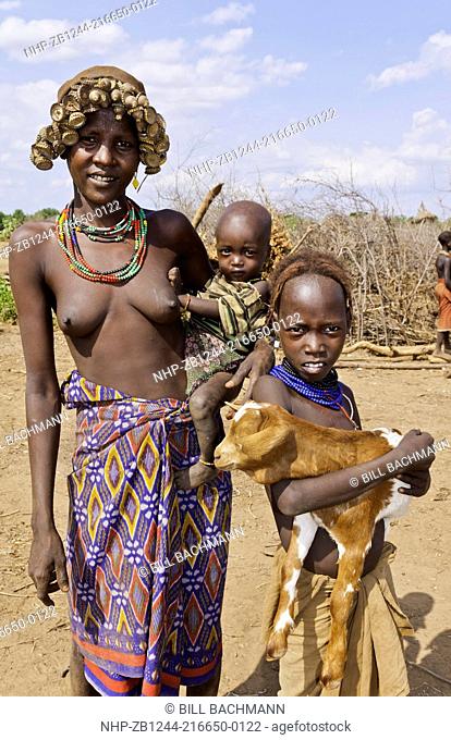 Dassnech Tribe in Omorate Ethiopia Africa Lower Omo Valley wife with children nude topless in village with headress 26