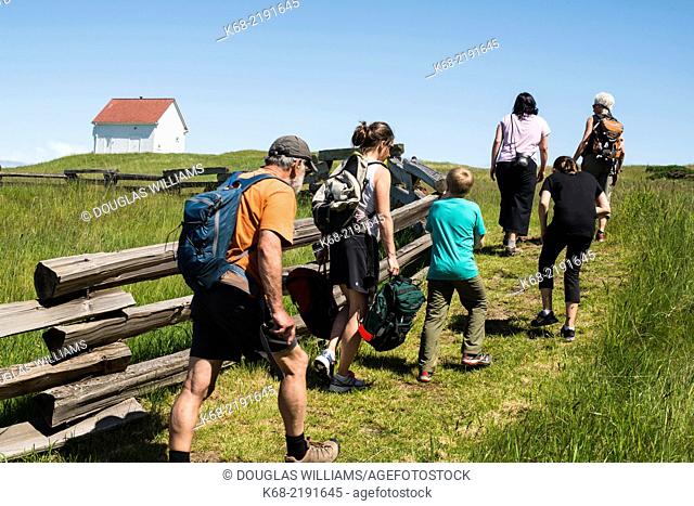 A group of people walk by the split rail fence, East Point Park, National Park Reserve, Saturna Island, Gulf Islands, BC, Canada