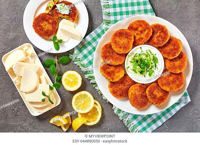 delicious crispy rice cutlets with crumbled paneer cheese and finely chopped greens on a white platter with yogurt sauce in center, indian recipe