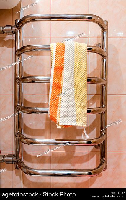 Stainless steel bathroom heated towel rail radiator, with a towel