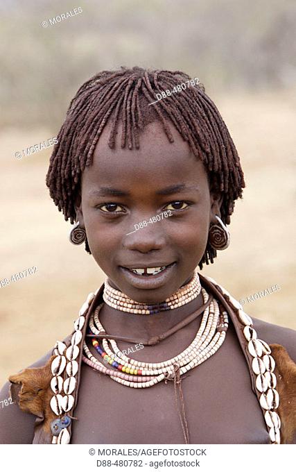 Girl Hamer tribe. Lower basin of Omo river. Copper skin with very fine features and wear metal arm and leg bracelets, shells and beads. South Ethiopia