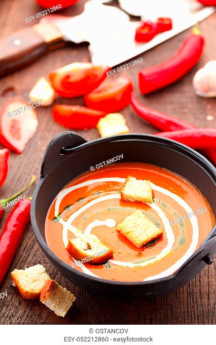 Tomato soup with croutons chili pepper and garlik on a wooden table