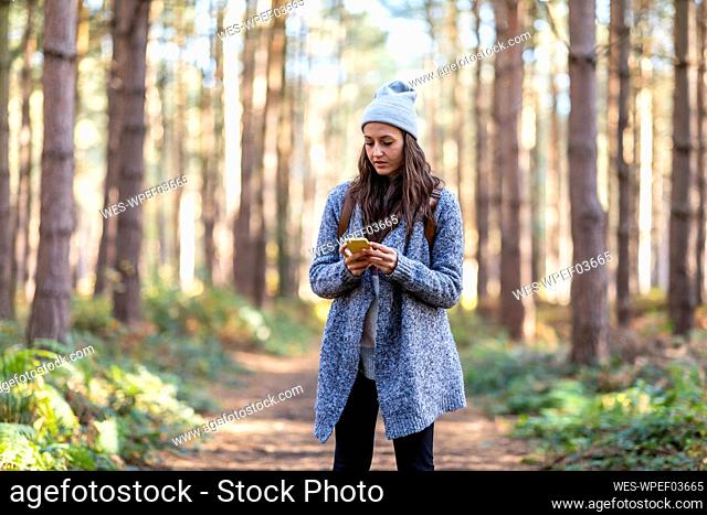 Female hike using smart phone while standing in Cannock Chase forest