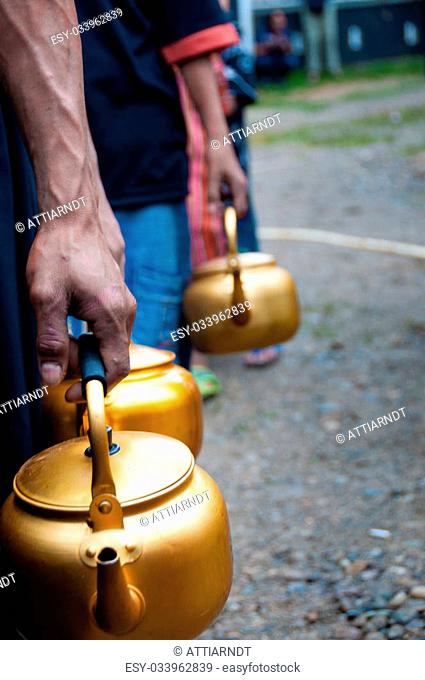 People of Sulawesi in Queue with golden pot in hand, during a funeral in Tana Toraja, Sulawesia, Indonesia