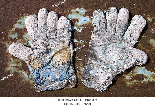 Pair of badly worn work gloves on rusty metal plate