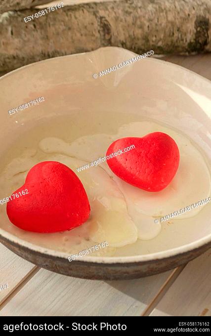 cooked egg with red hearts in a fryer, concept of belarusian revolution, vertical image