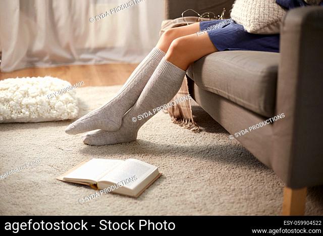 woman in socks with book on floor at home