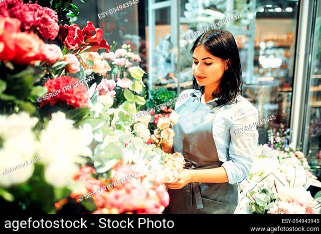 Female florist selects flowers for making a bouquet in floral shop. Floristry service, floristic business