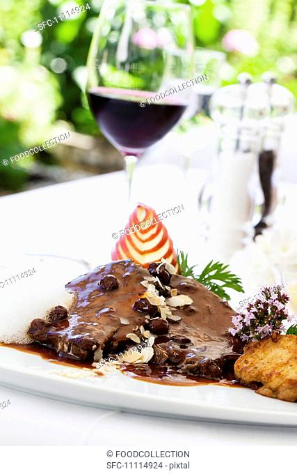 Rhenish Sauerbraten marinated pot roast with raisins and napkin dumplings and a glass of red wine