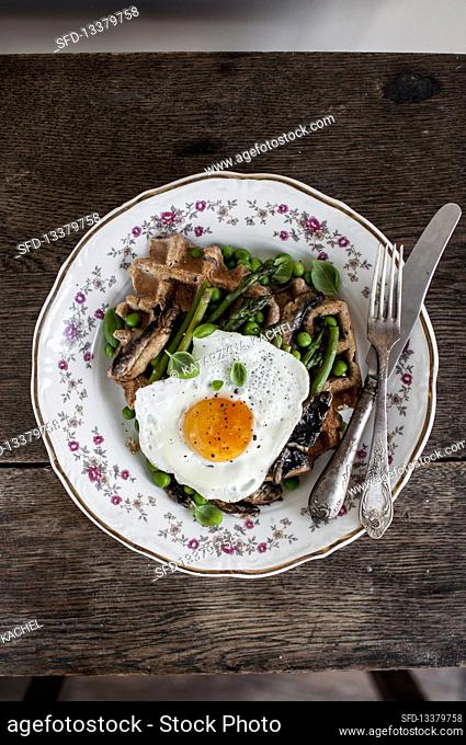 Buckwheat waffle with green asparagus, green peas, fried portobello mushrooms, fried egg and fresh basil leaves