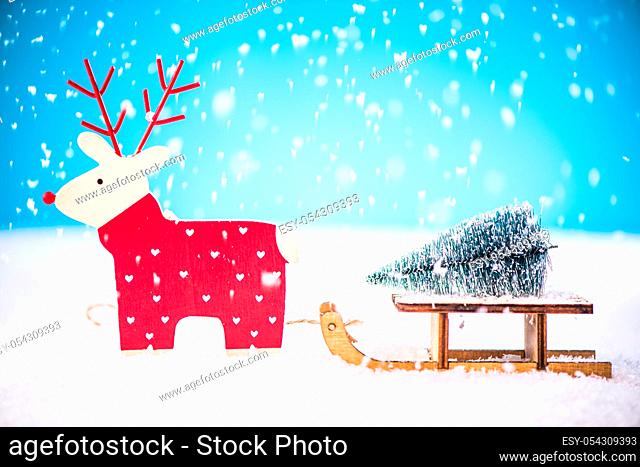 Funny reindeer carry Christmas tree on snow sledge