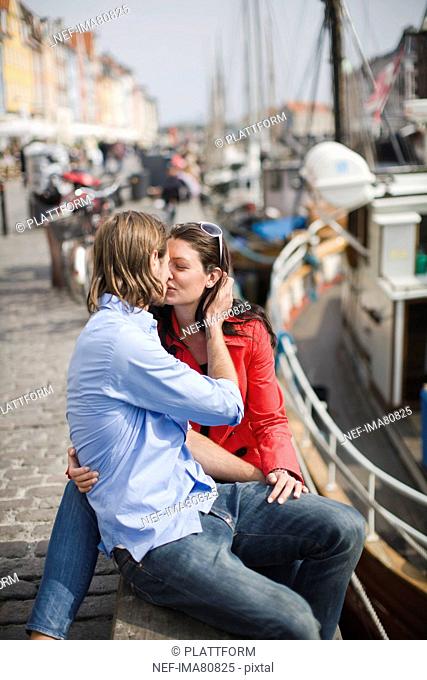 Young couple sitting on pavement and kissing