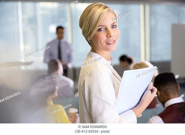 Portrait smiling businesswoman with paperwork in conference room meeting