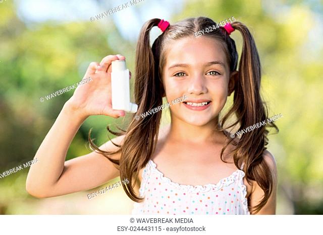 Girl holding an asthma inhaler in the park