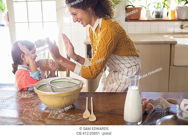 Mother and daughter high fiving in the kitchen