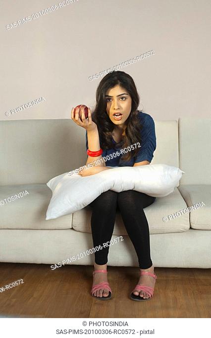 Woman holding an apple and watching tv