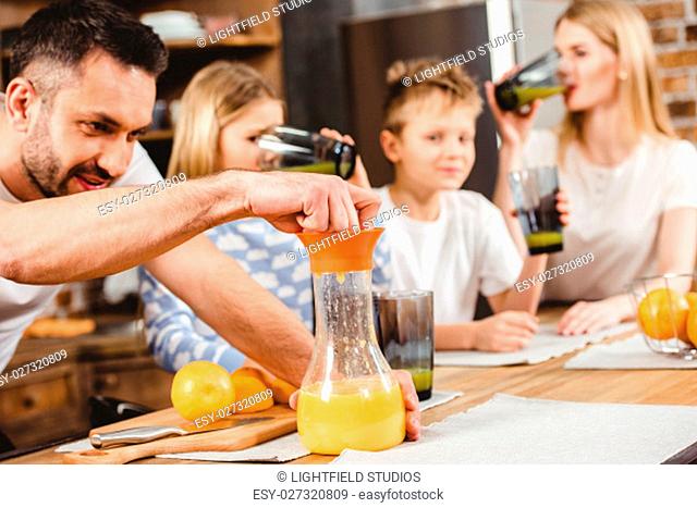 Young man makes orange juice for his family for breakfast