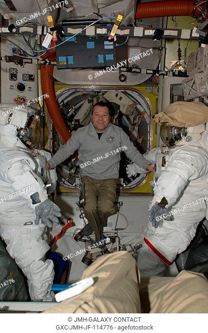NASA astronaut Nicholas Patrick, STS-130 mission specialist, poses for a photo between two Extravehicular Mobility Unit (EMU) spacesuits in the Quest airlock of...