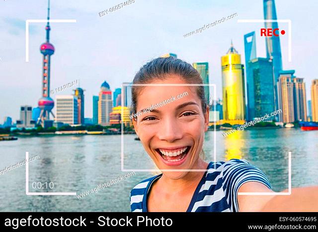 Happy China travel selfie Asian tourist woman vlogging online recording videoblog vlog video. Smiling young girl holding camera phone at the Bund at Shanghai's...