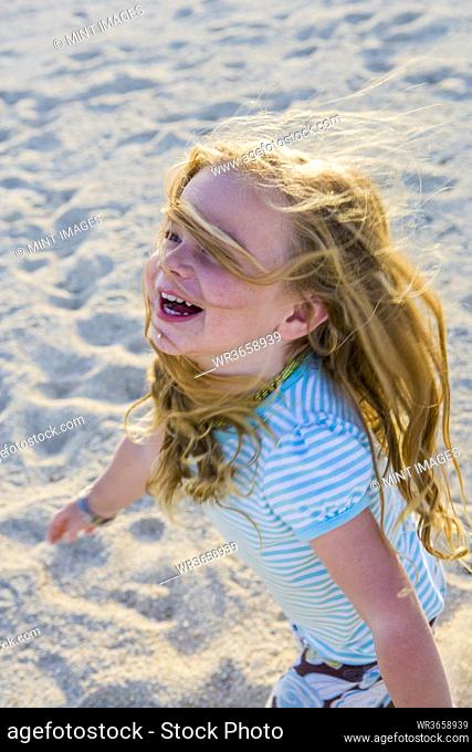 laughing 3 year old girl running in the sand