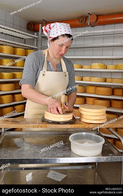 Germany, Baden Wuerttemberg, Mid adult woman sprinkling salt water on cheese