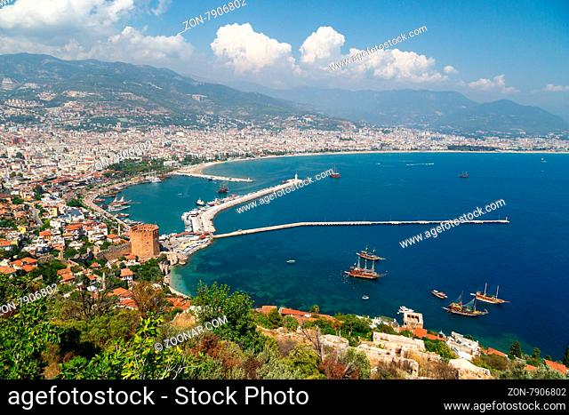ALANYA, ANTALYA - AUGUST 16, 2015 : View of Alanya city on coastline with sailing boats and yachts in the sea, on cloudy blue sky background