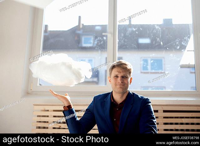 Smiling businessman with levitating cloud network in office