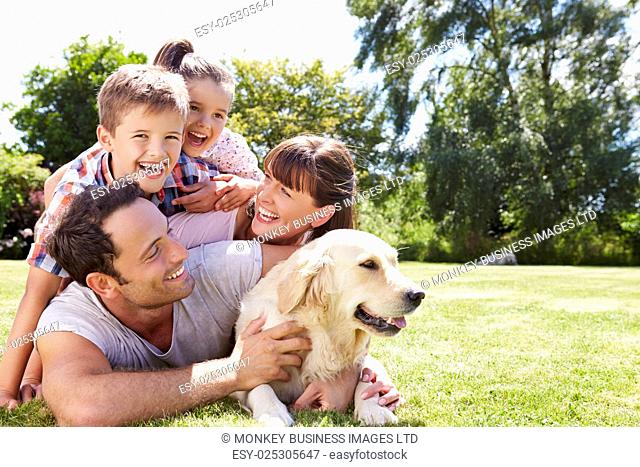 Family Relaxing In Garden With Pet Dog