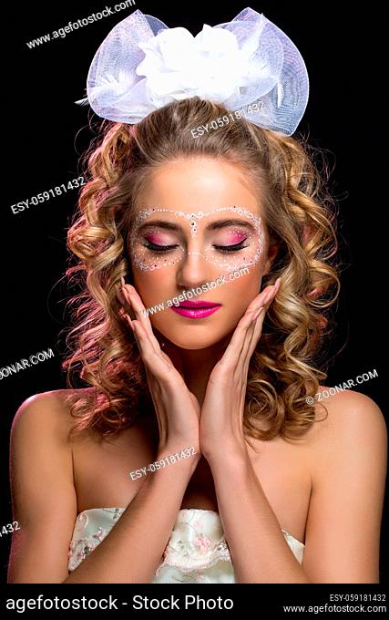 Beautiful young woman with make-up and mask drawn around eyes. Bride with big white bow on head. Beauty closeup shot
