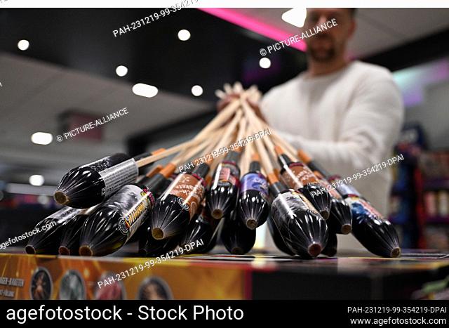 PRODUCTION - 19 December 2023, North Rhine-Westphalia, Eitorf: An employee holds New Year's Eve rockets in the showroom of the fireworks company Weco