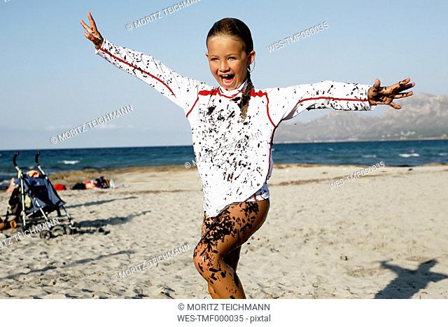 Spain, Mallorca, laughing little girl covered with seaweed on the beach