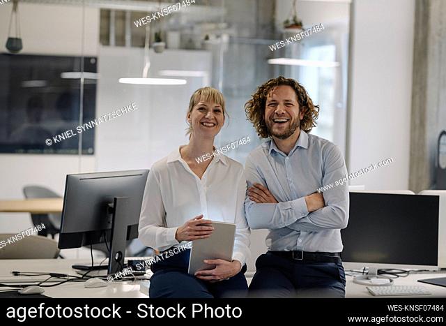 Portrait of happy businessman and businesswoman with tablet in offce