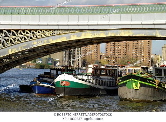Boats underneath Battersea Reach Railway Bridge with Chelsea Harbour in the distance, London, England