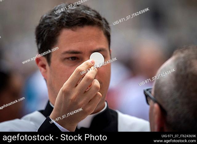 A priest gives holy communion during Pentecost Holy Mass in St. Peter's Square, at the Vatican