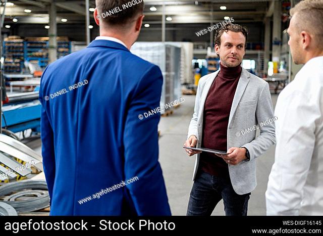 Businessman with digital tablet having discussion with colleague in industry