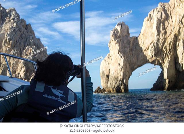 A tourist taking a photo at sea from the boat of the Land's End in Cabo San Lucas. Los Arco is the symbol of Cabo San Lucas, Mexico