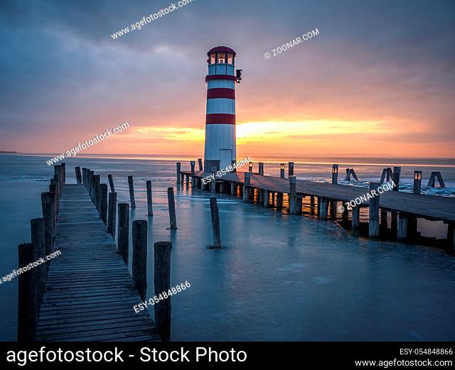 Winter landscape with lighthouse on a lake at sunset