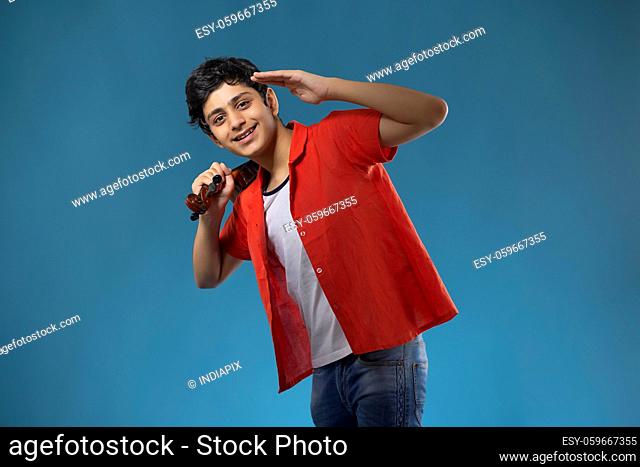 A STYLISH TEENAGE BOY POSING IN FRONT OF CAMERA WHILE HOLDING VIOLIN