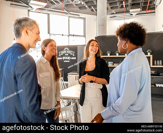Happy businessman talking with businesswomen in cafeteria