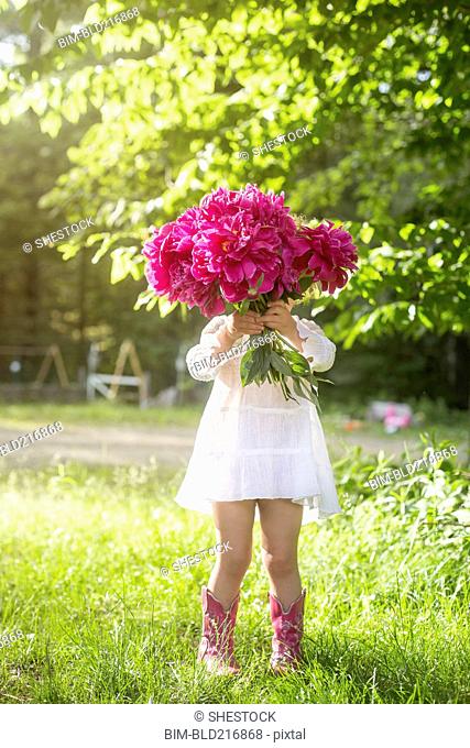 Girl holding bouquet of flowers in backyard