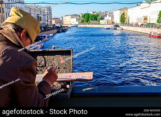 St. Petersburg, Russia - May 22, 2014: a street artist paints river landscape on the bridge over the Neva River