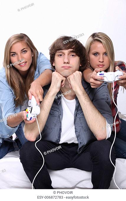 Bored teenager sat between two friends playing video games
