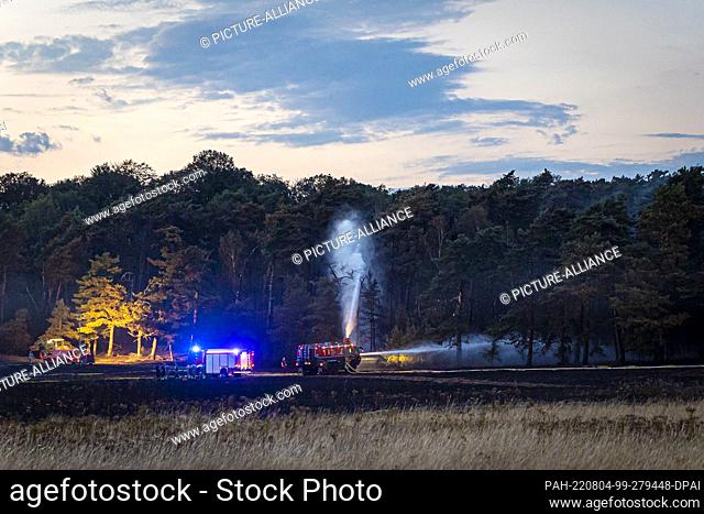 04 August 2022, Lower Saxony, Königslutter am Elm: Firefighters use an airfield fire engine (r) to fight a forest fire in the Helmstedt district