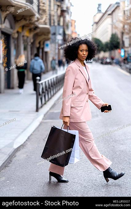 Young businesswoman walking with shopping bags on street