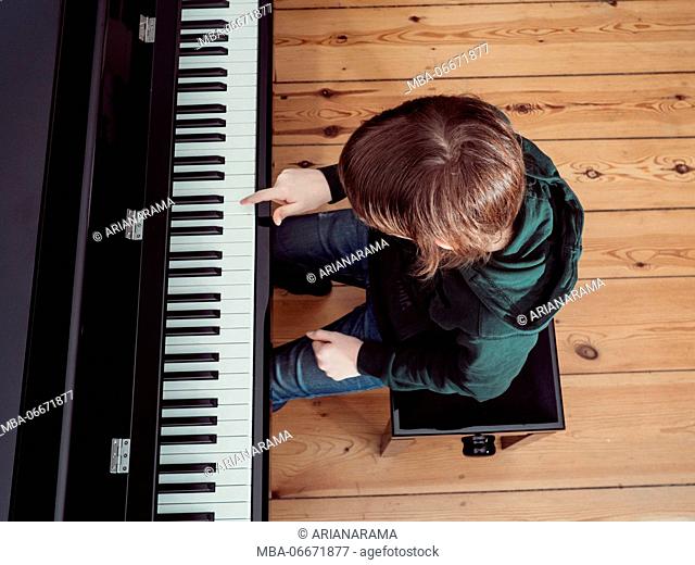 Portrait of a boy playing on a black digital piano - high angle view