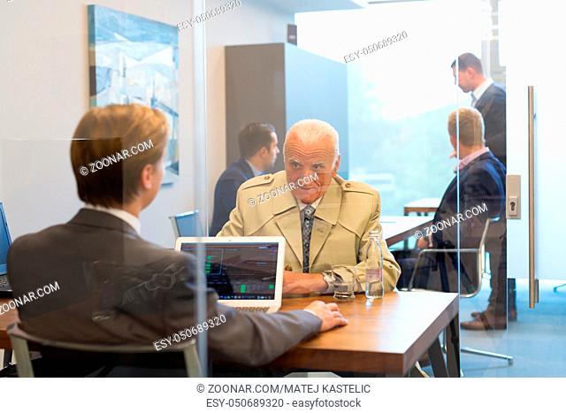 Young financial advisor sitting in front of laptop, consulting senior client with his investment strategy. Business people on business meetings